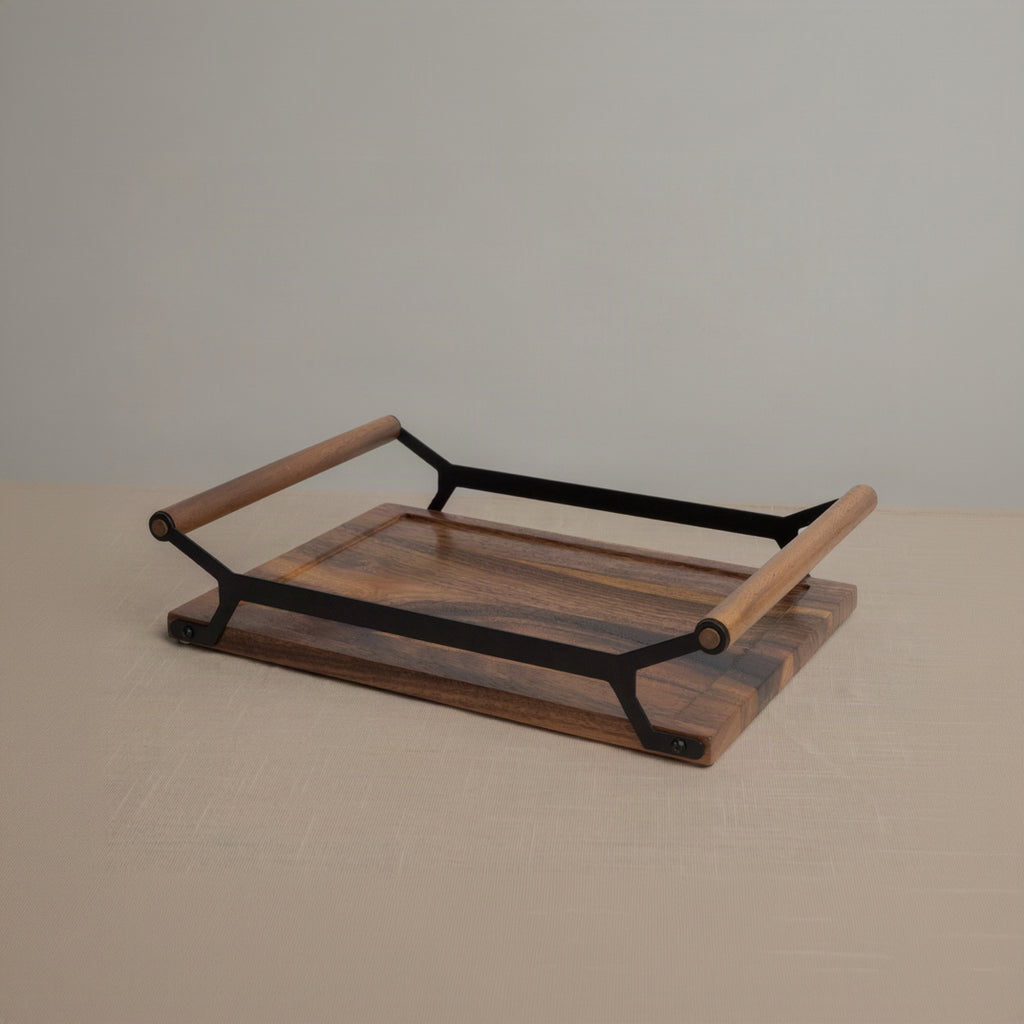 A rectangular wooden serving tray with a rich medium-brown wood grain and a black metal frame with light wood handles, set against a neutral beige background.
