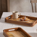 Two wooden trays on a table with a cup and pastries on one tray.
