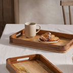 Two wooden trays on a table with a cup and pastries on one tray.