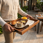 Person holding a tray with breakfast items in an outdoor setting